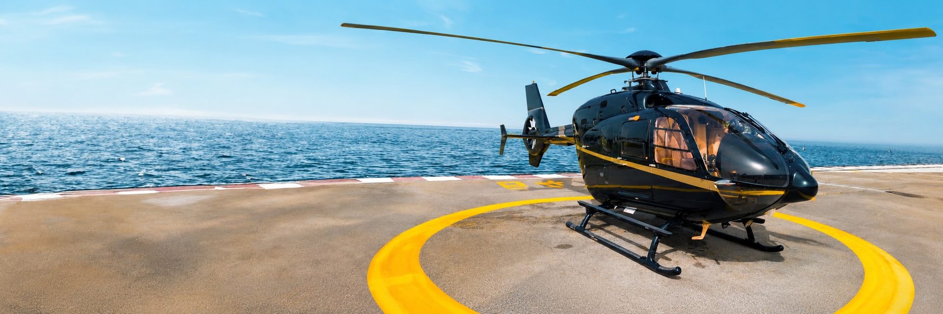 Accueil VIP à l'héliport de Monaco — un hélicoptère privé sur l'aire d'atterrissage, berline de la Maison en attente.