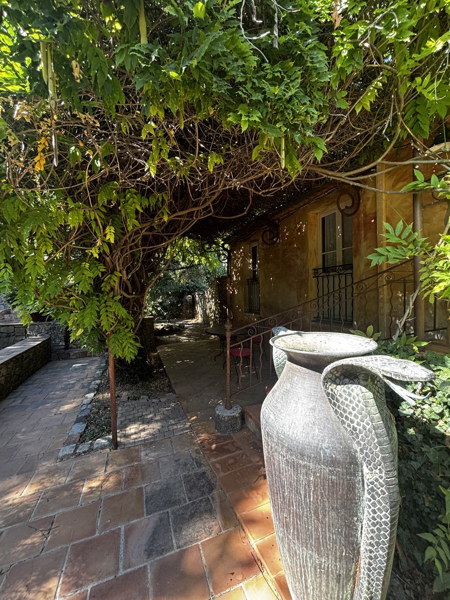 The wisteria pergola and antique amphora before the ochre façade.