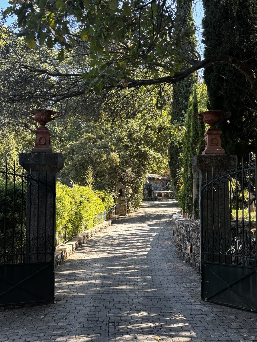 The wrought-iron gate and its Medici urns opening onto the drive.
