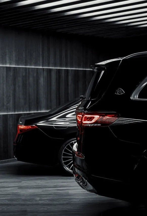 Chauffeur de la Maison Vehira en attente discrète, près d'une berline noire stationnée sur la Côte d'Azur.