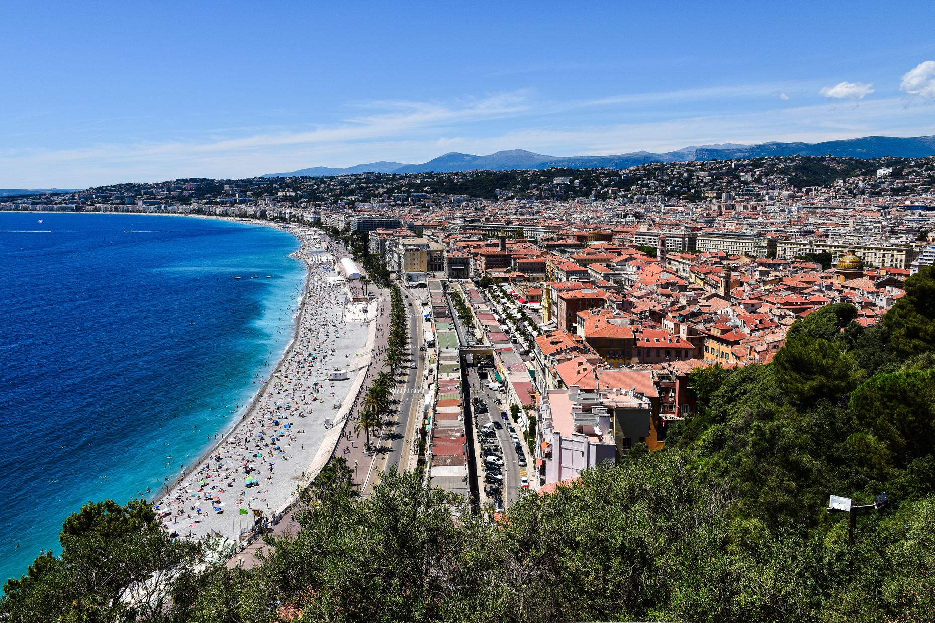The Baie des Anges and Promenade des Anglais in Nice — beach, Old Town and hills seen from Castle Hill.
