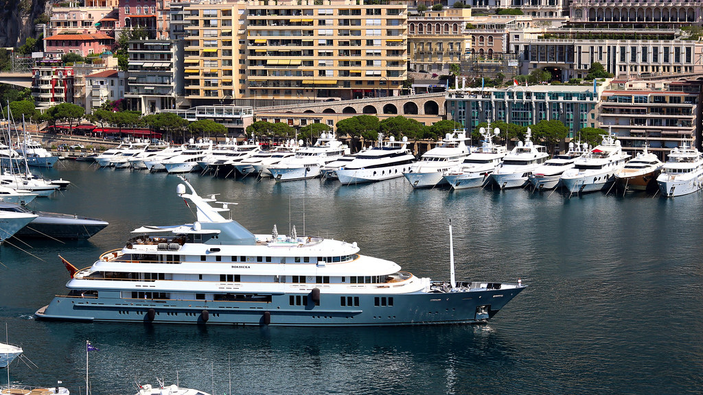 Vue du Port Hercule de Monaco — yachts amarrés, le Rocher en arrière-plan, scène quotidienne de la Maison.