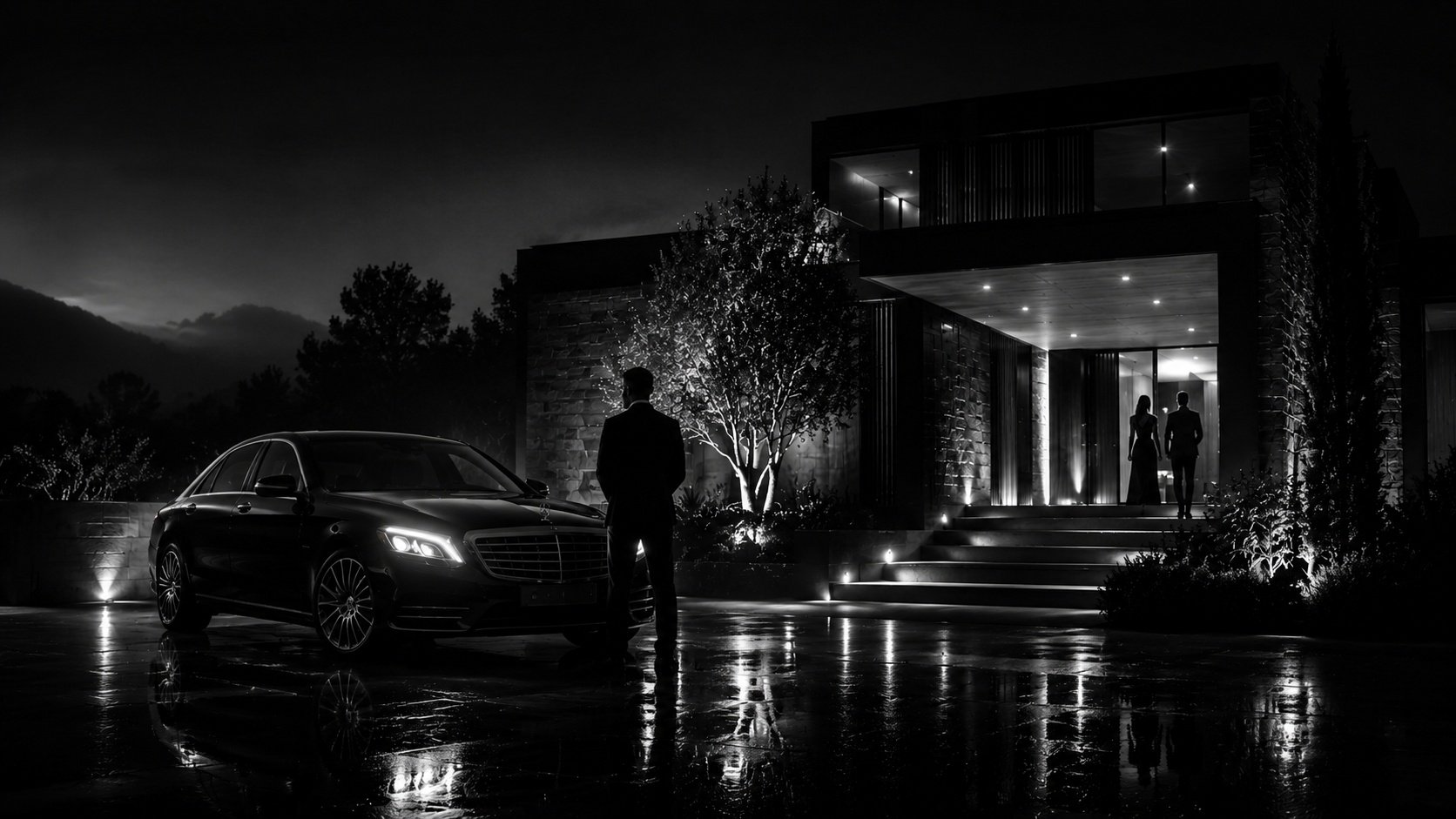 Chauffeur de la Maison Vehira en costume sombre, à la portière ouverte d'une berline noire devant une villa de la Côte d'Azur.